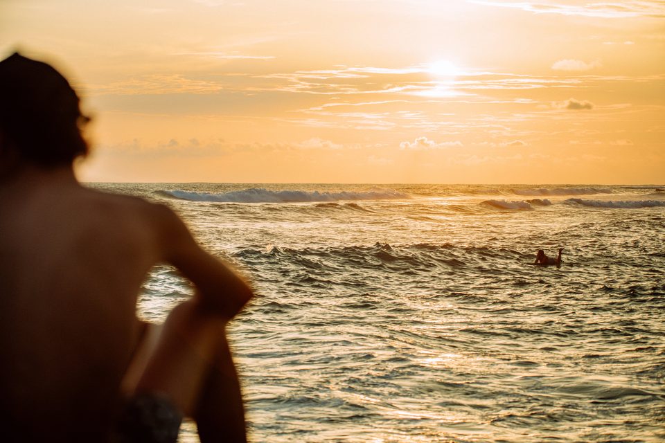 Watching the surfers from the beach at sunset