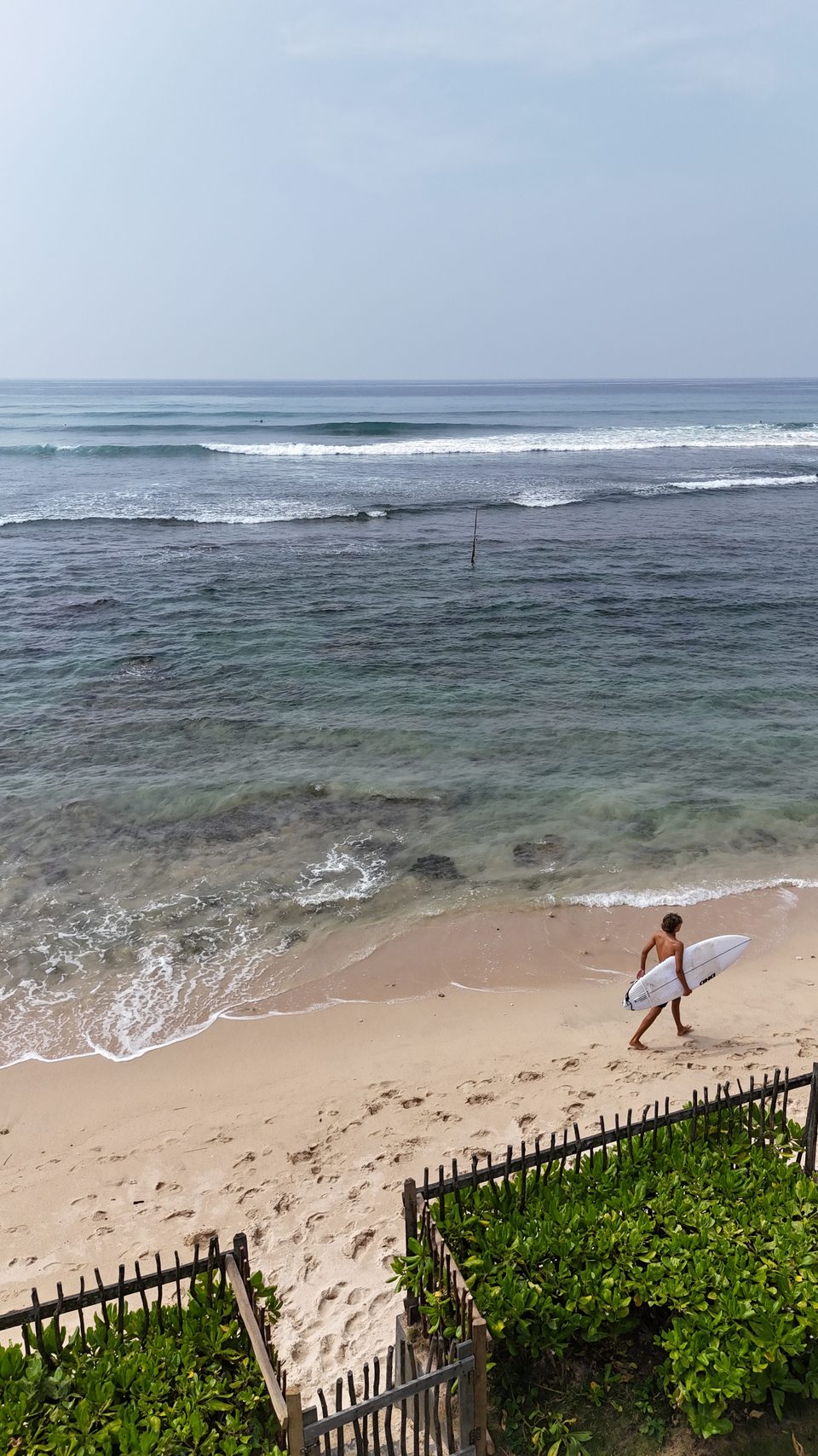 A lone surfer walking the beach at Ahangama