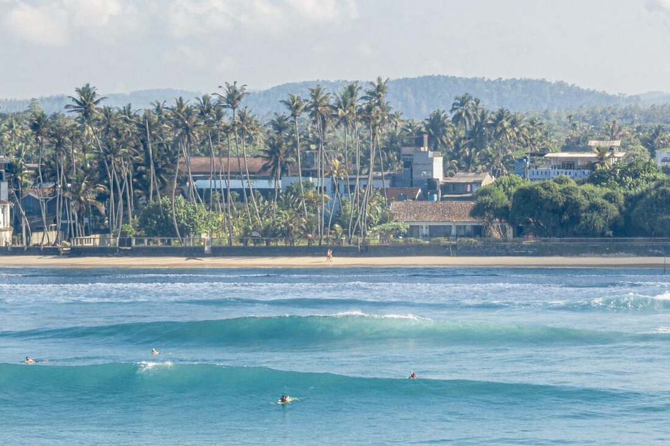 Surfers on the reef break along the Ahangama coast